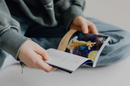 Ein Kind liest aus dem Begleitbuch zu den Krafttierkarten für Kinder und entdeckt die spirituelle Botschaft eines Tieres. Das Buch beinhalten eine persönliche Ansprache, eine Botschaft und eine praktische Übung zur Förderung von Achtsamkeit und Körperbewusstsein. Entwickelt von Physiotherapeutin Jennifer Kühnel, verbindet dieses Set Krafttiere mit physiotherapeutischen Übungen, um die körperliche Entwicklung bei Kindern zu unterstützen.